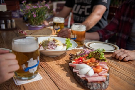Auf einem Tisch steht schön angerichtet ein bayerische Brotzeit mit Wurst und Käse.