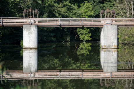 Das Bild zeigt eine Schleuse aus Holz am Alten Kanal, die sich im Wasser spiegelt.