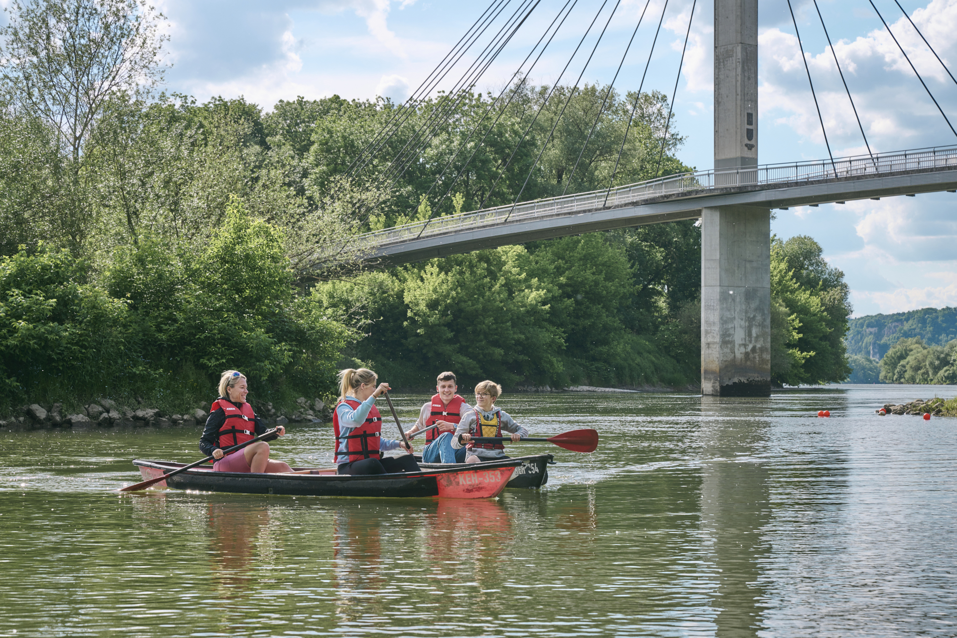 Eine vierköpfige Familie paddelt mit zwei Kanus auf der Donau bei Bad Abbach.