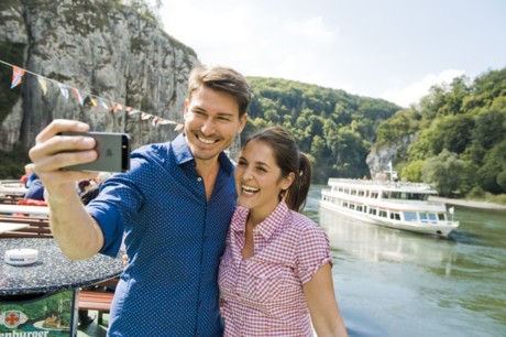 Ein junges Pärchen fährt auf dem Schiff durch den Donaudurchbruch und macht ein Selfie.