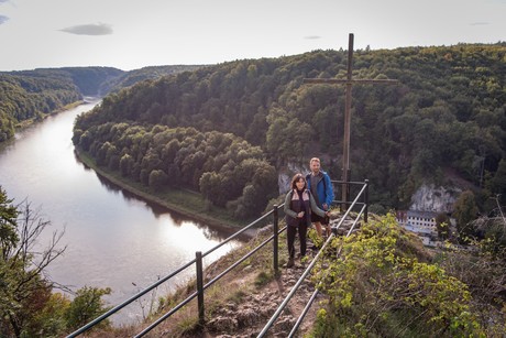 Zwei Wanderer genießen bei einer Wanderung im Nationalen Naturmonument Weltenburger Enge den Blick auf die Donau.