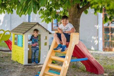 Spielplatz mit Spielhaus, Rutsche und zwei Kindern im Biergarten vom Stanglbräu.