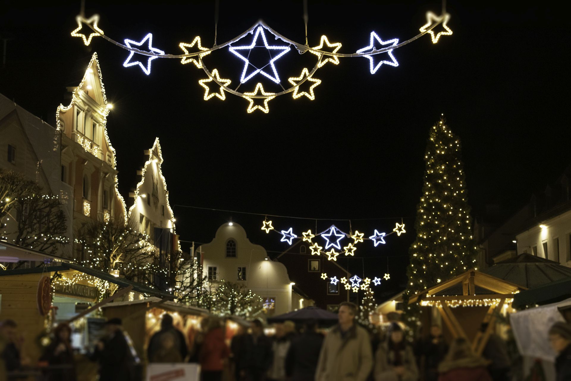Der Kelheimer Stadtplatz erstrahlt am Christkindlmarkt mit zahlreichen Lichtern. Zahlreiche Menschen genießen an den Ständen Glühwein und weihnachtliche Schmankerl.