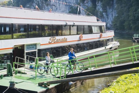 Eine Frau und ein Mann gehen mit ihren Fahrrädern von Bord eines Ausflugsschiffes in Weltenburg.