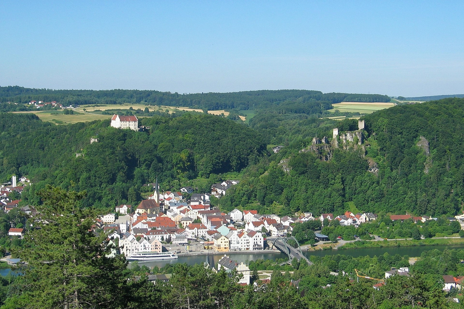 Blick auf die im Tal liegende Altstadt Riedenburgs. Hoch über der Stadt stehen die Rosenburg und die Burgruinen Rabenstein und Tachenstein.