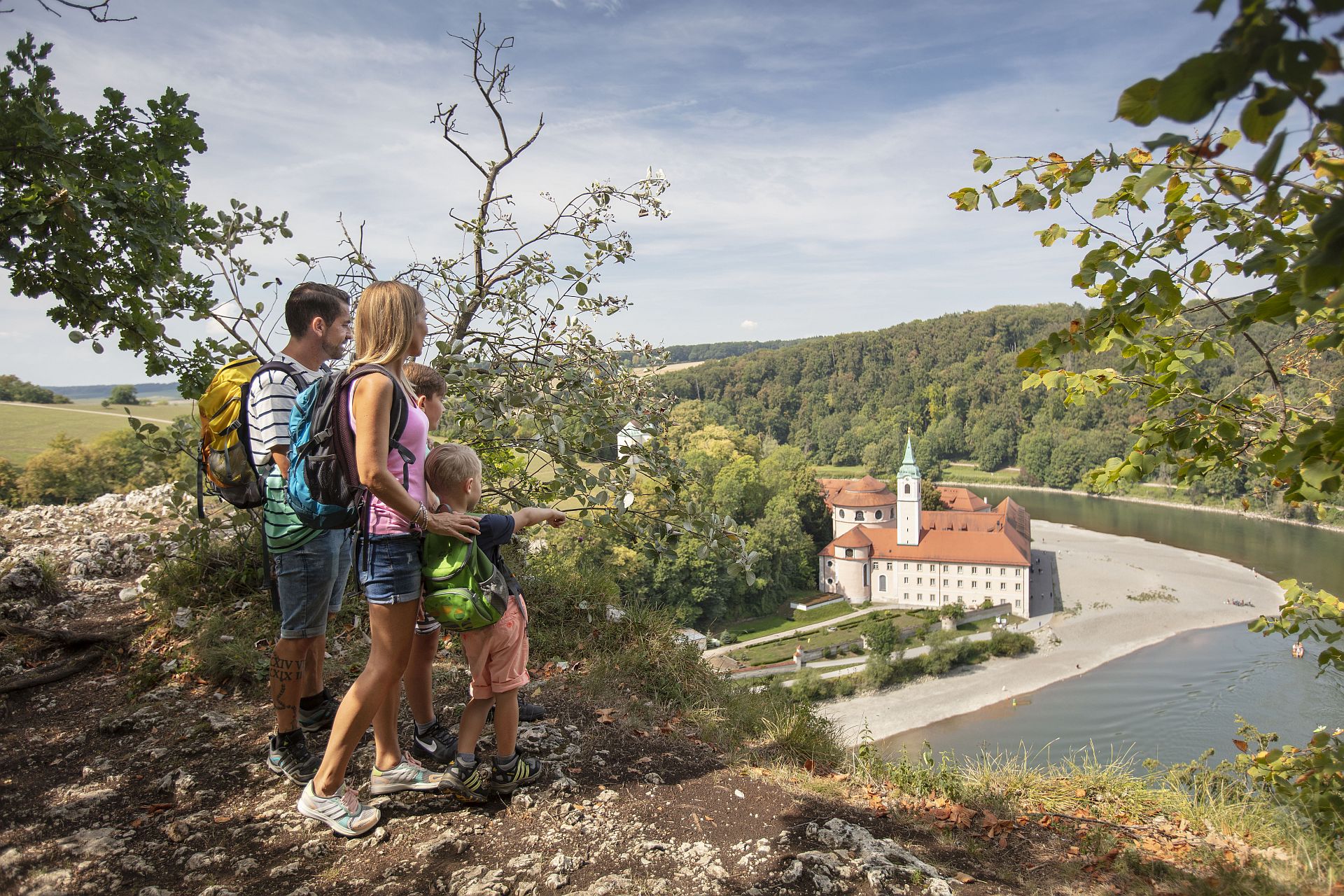 Eine Familie genießt den Ausblick von einem Felskopf der "Weltenburger Enge" auf das Kloster Weltenburg an der Donau.