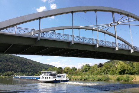 Ein Frachtschiff fährt auf dem Main-Donau-Kanal in Riedenburg. Über ihm ist die St.-Anna-Brücke zu sehen.